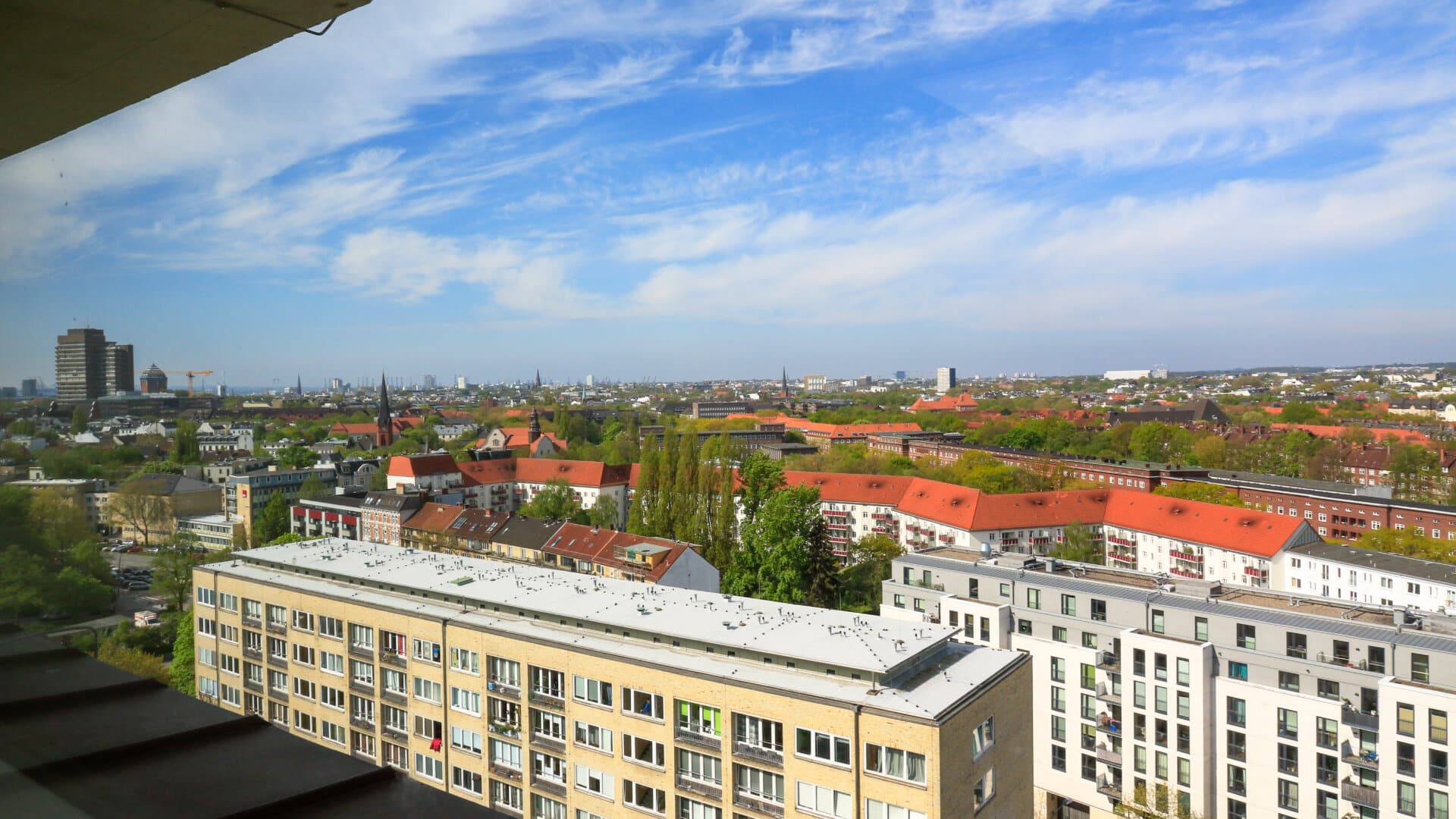 Blick über Hamburg mit Wohngebäuden im Vordergrund und Stadtpanorama unter blauem Himmel