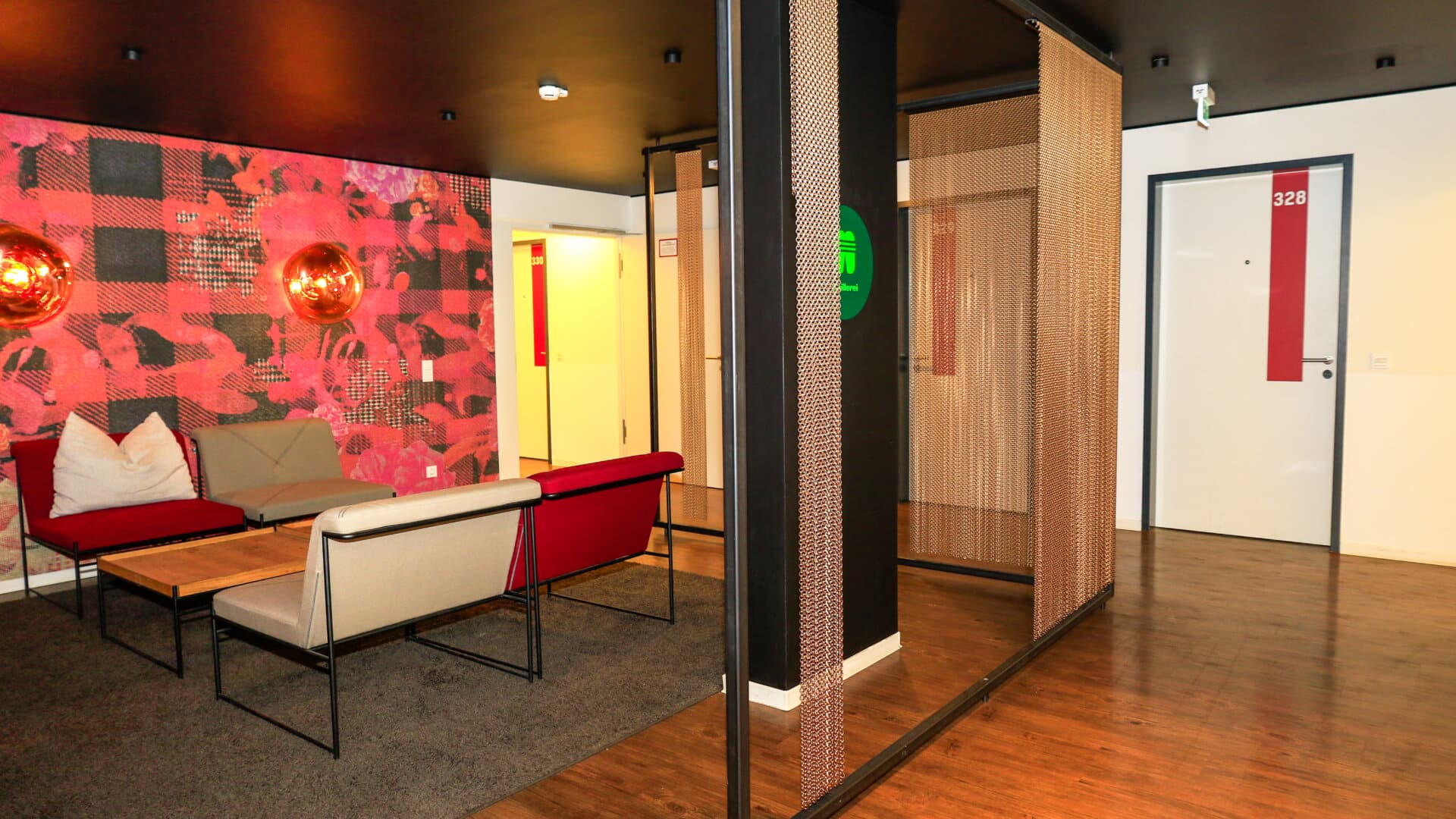 Sitzbereich mit roten und grauen Sofas, Holztisch und roter Wandgestaltung in einem modernen Flur mit Tür Nummer 328